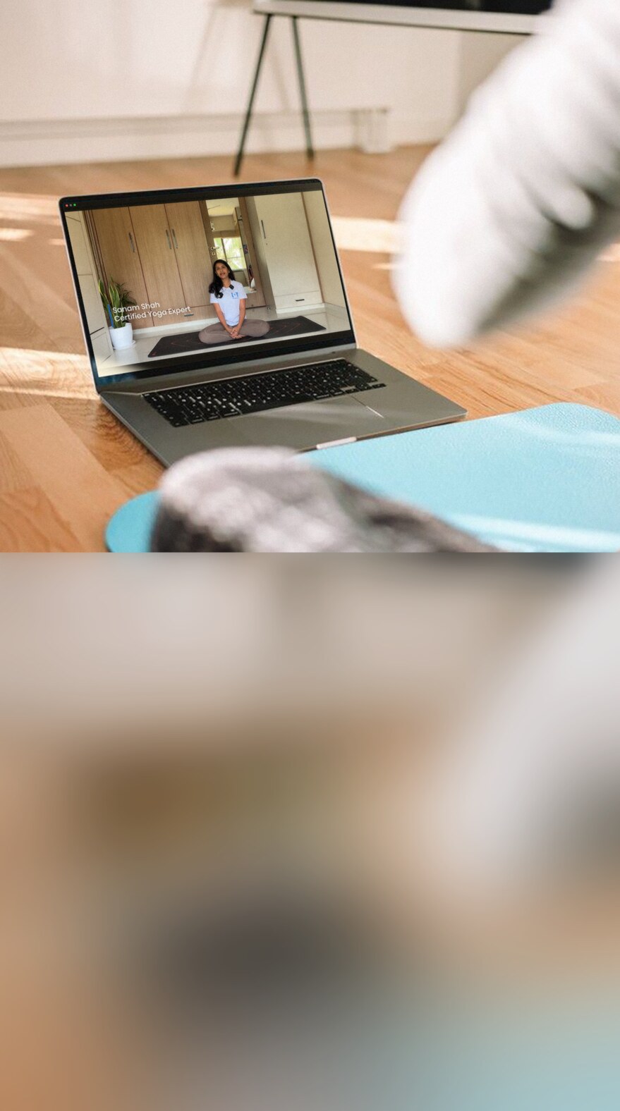 Following a guided physiotherapy session on a laptop from a yoga mat at home.